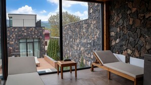 Et moderne værelse med stenvæg, store vinduer og en balkon.