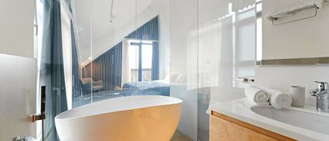 A modern bathroom with a freestanding bathtub, a wooden vanity, and a glass shower enclosure.
