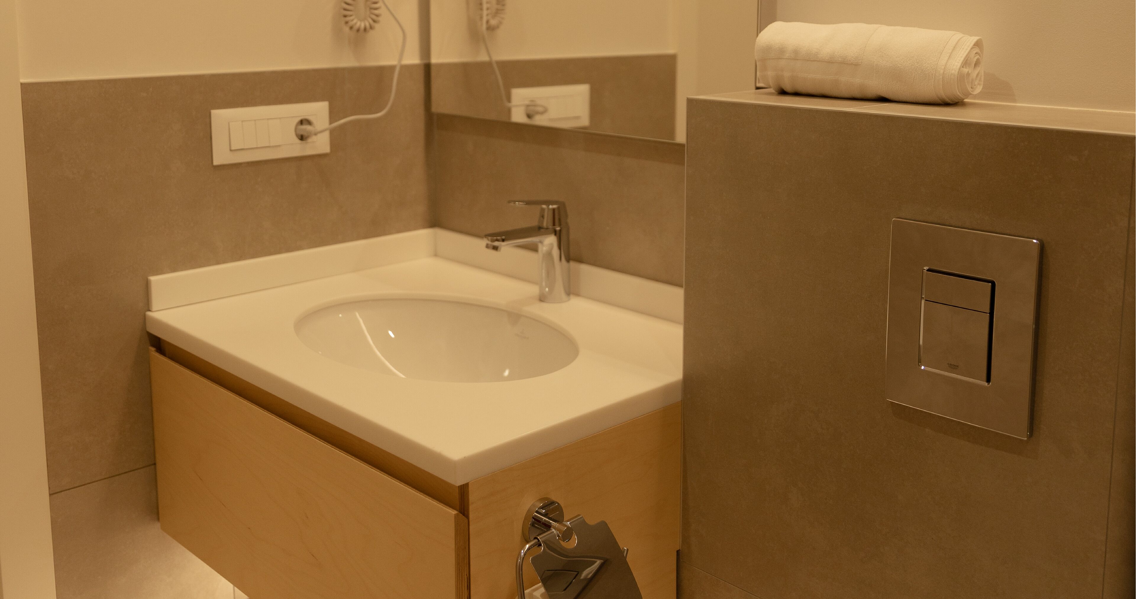 Ein modernes Badezimmer mit Waschbecken, Spiegel, Handtuchhalter und einem Handtuch an der Wand.