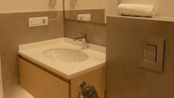 A modern bathroom with a sink, mirror, towel rack, and a towel on the wall.