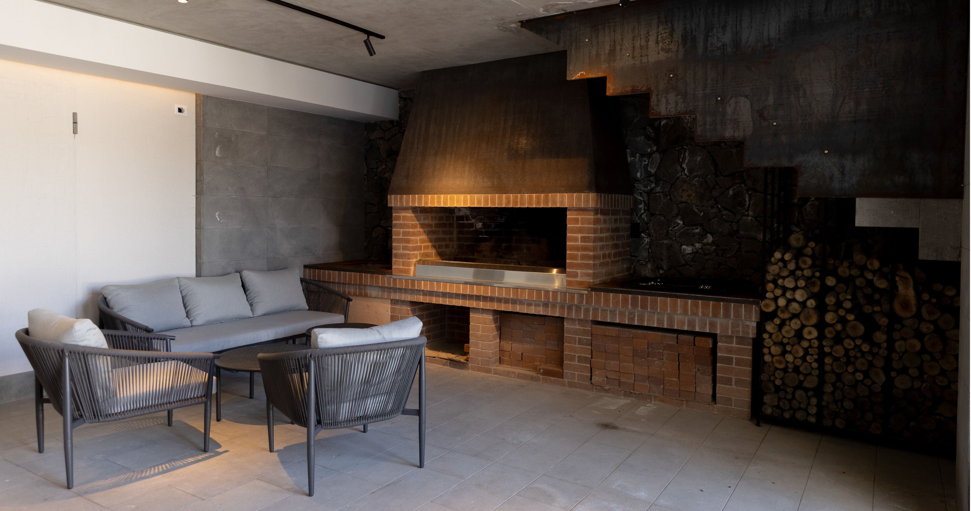 An outdoor seating area with a brick fireplace and a stone wall.