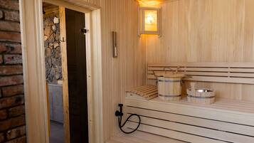 Una sauna de madera con bancos, un muro de piedra y un ventanal.