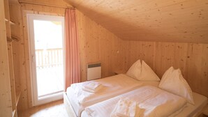A wooden room with two beds, a window, and a door. - Nice chalet with infrared sauna (Sankt Georgen am Kresichberg)