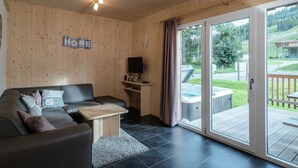 A cozy living room with a wooden interior, a sofa, a coffee table, and a TV on a stand.