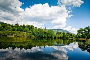 Um rio calmo refletindo o céu e o verde da vegetação ao redor.