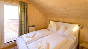 Una habitación con dos camas individuales, paredes de madera, una ventana con cortinas y techo de madera.