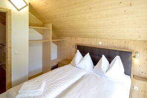 A wooden-paneled room with a bed, white towels, and a headboard.