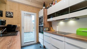 Una cocina moderna con paredes de madera, gabinetes blancos y encimera de madera.