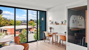 A modern room with large windows, a dining area, and a kitchenette. - Reluxme|European Flat Near Uptown King Bed + Views (Charlotte)