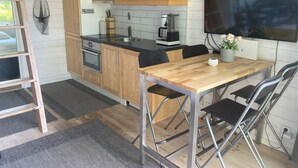Ett modernt kök med träskåp, en inbyggd ugn, en kaffemaskin och en matplats med ett träbord och stolar.