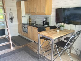 Una cocina moderna con armarios de madera, horno empotrado, cafetera y comedor con mesa y sillas de madera.