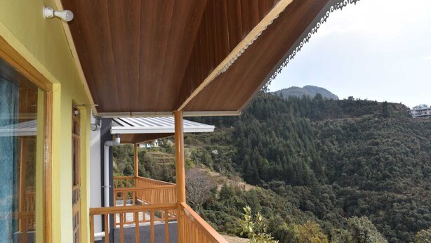 A wooden balcony with a view of a forested hillside.