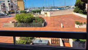 Blick auf eine Marina mit mehreren dort vertäuten Segelbooten. Ein Gebäude mit Balkonen und ein Restaurantschild sind sichtbar.