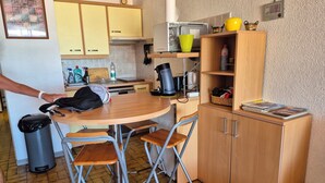 Eine kleine Küche mit Holzschränken, einem Esstisch und klappbaren Stühlen.