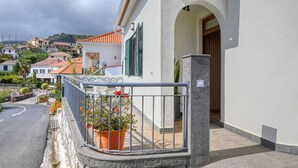 En boligbygning med balkon, en stensøjle og udsigt over kvarteret.