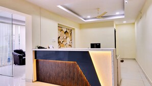 Un comptoir d’accueil moderne agrémenté d’un élément décoratif en bois, d’un ventilateur de plafond et d’une cloison en verre.