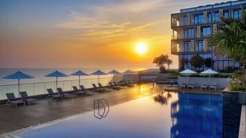 Een buitenzwembad, parasols bij het zwembad en ligstoelen