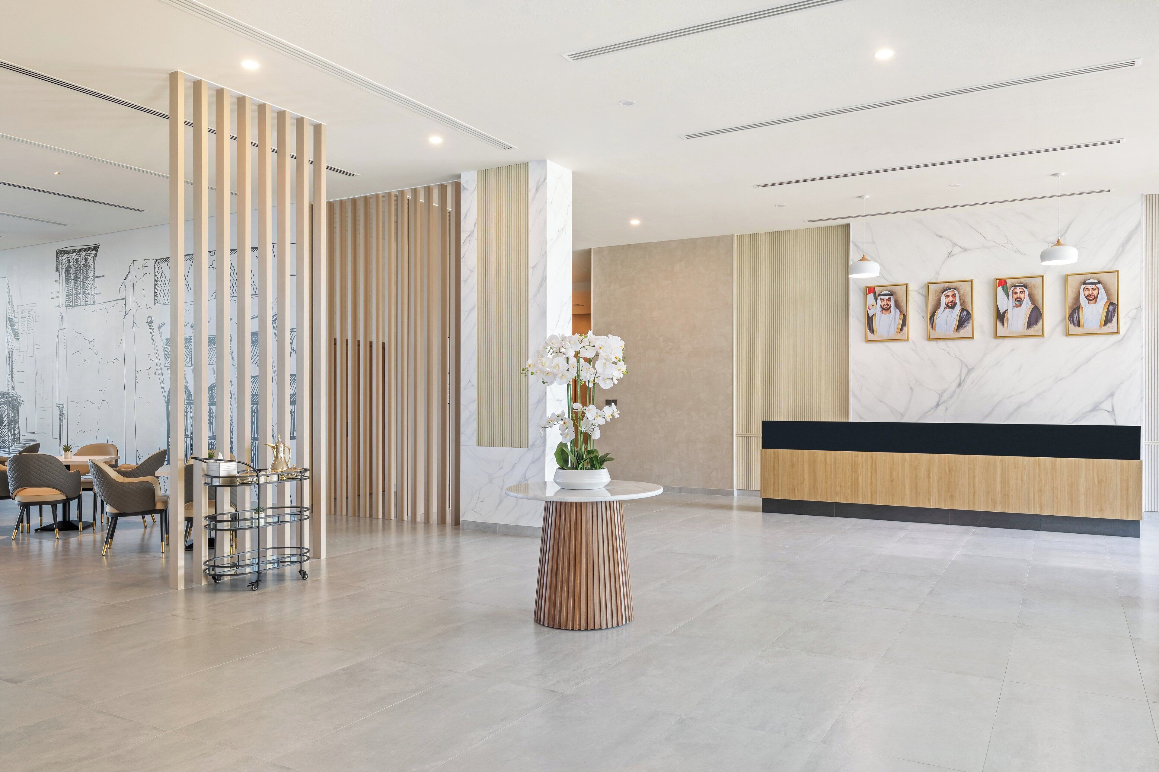 A modern reception area with a marble reception desk, a potted orchid, and a seating area with chairs and a small table.