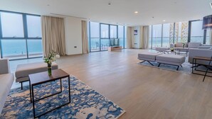 Un salón amplio con un gran ventanal con vistas al mar, un área de descanso confortable y un televisor de pantalla plana.