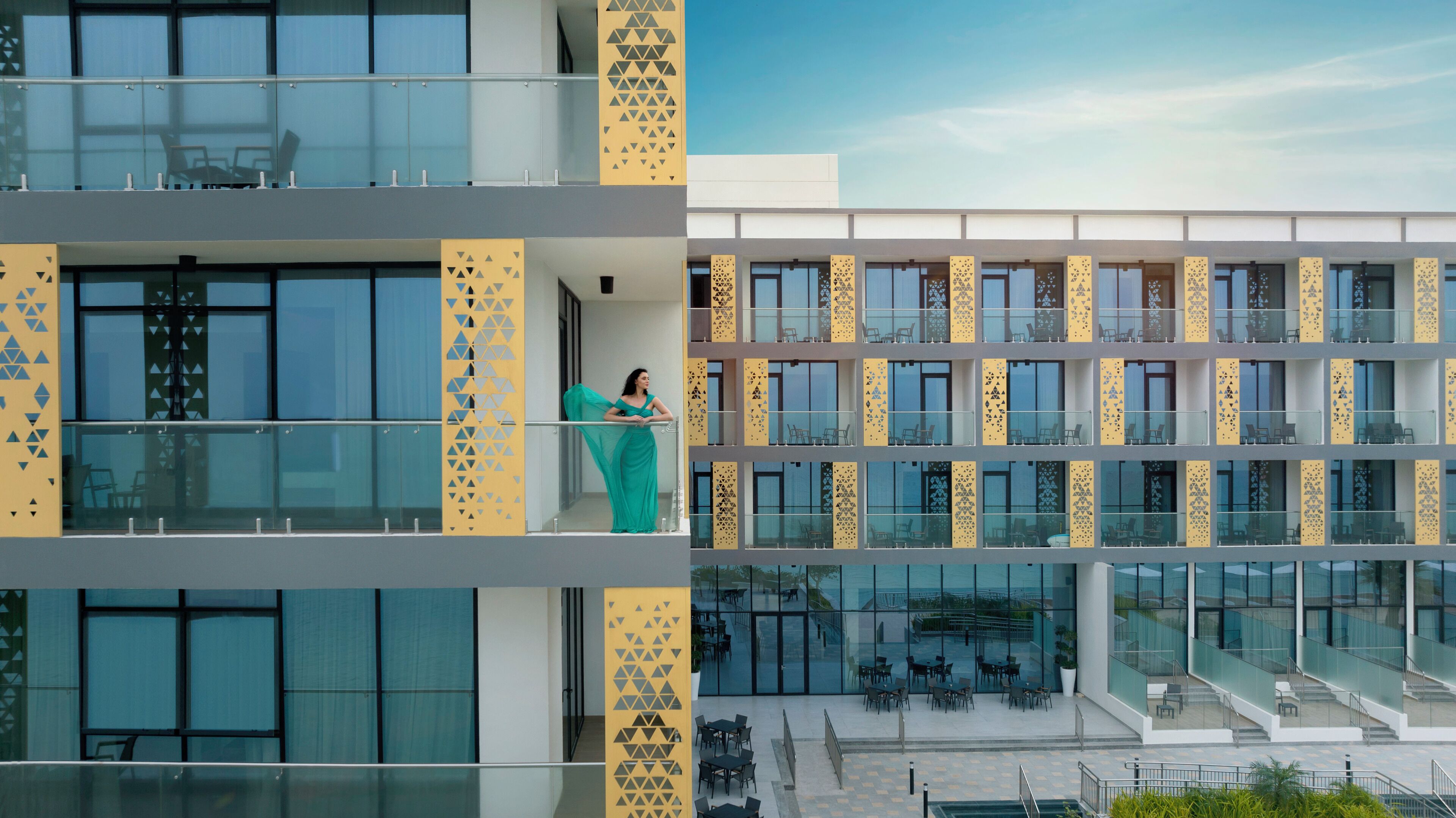 Un hôtel moderne doté de nombreux balcons, d’une façade en verre et d’espaces extérieurs aménagés pour se détendre.