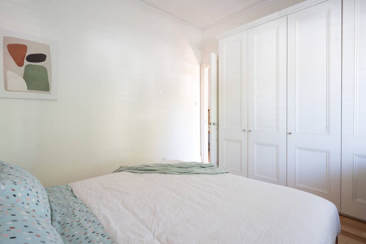 Een slaapkamer met een bed, een kledingkast en een schilderij aan de muur.
