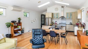 Une cuisine moderne avec un coin repas, un plancher en bois et une bibliothèque.
