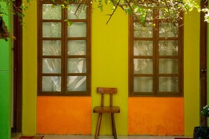 A room with two windows, a wooden chair, and a green wall. - Casa Felicisima Inn (Puerto Princesa)