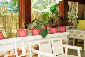 A balcony with potted plants, a white chair, and a table with a patterned tablecloth. - Casa Felicisima Inn (Puerto Princesa)