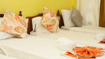 Habitación de hotel con dos camas, ropa de cama blanca y una pared amarilla.