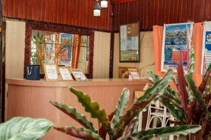 A reception desk with a wooden counter, framed certificates, and a bulletin board with tour information. - Casa Felicisima Inn (Puerto Princesa)