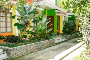 A residential building with a stone pathway leading to the entrance, surrounded by lush greenery and a variety of plants. - Casa Felicisima Inn (Puerto Princesa)