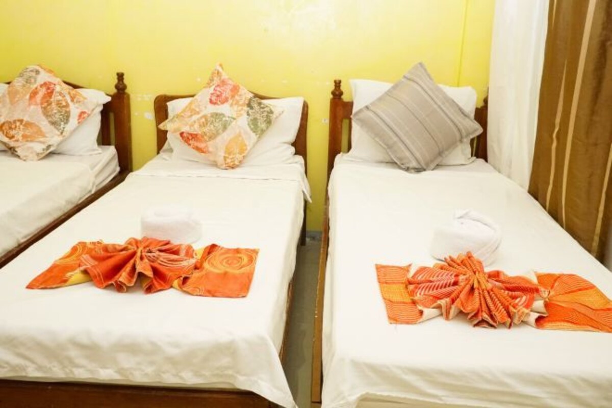 A hotel room with two single beds, each with a neatly folded towel and a decorative orange towel on the bed.