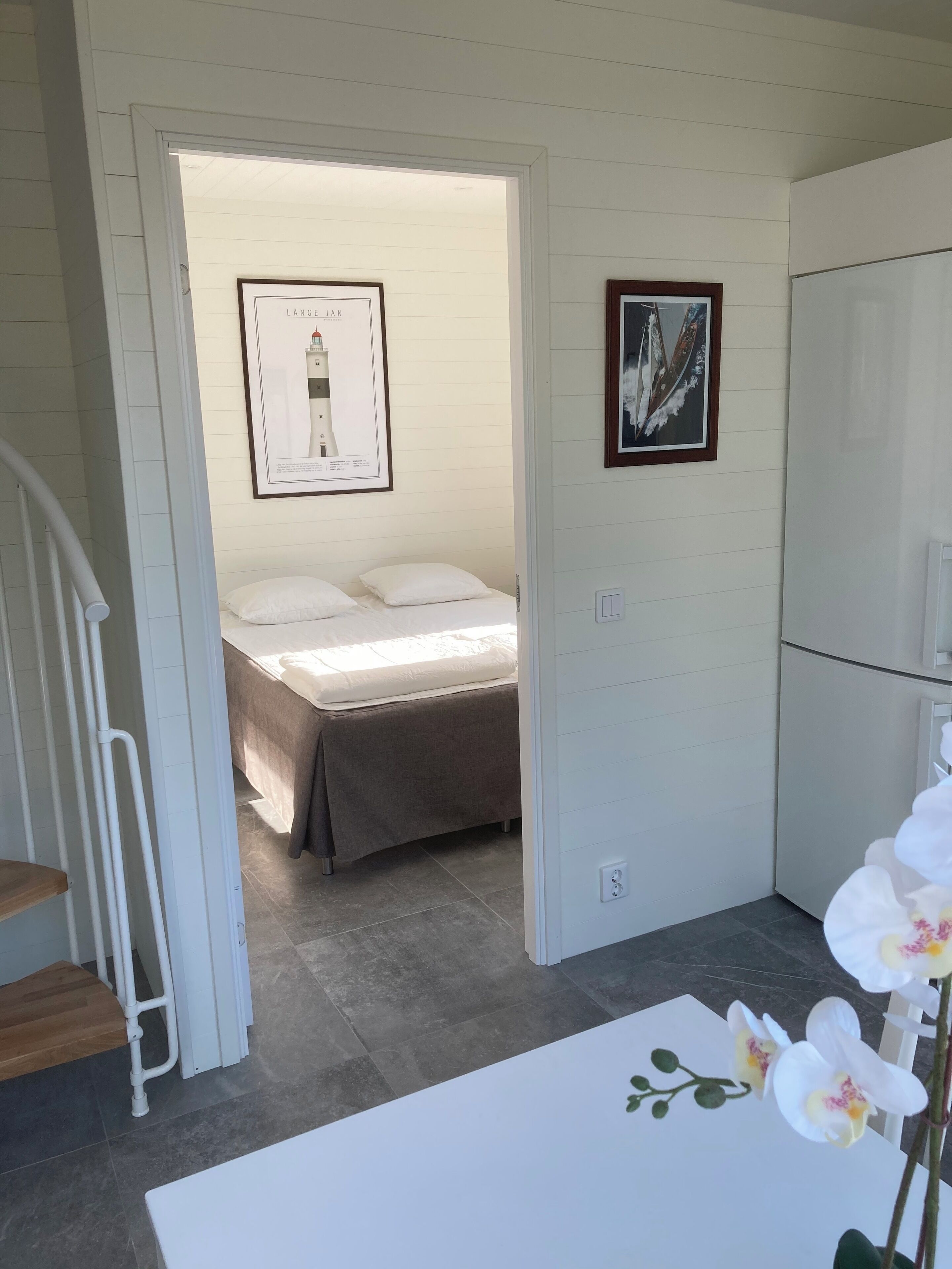A bedroom with a bed, a framed picture on the wall, and a white door leading to another room.