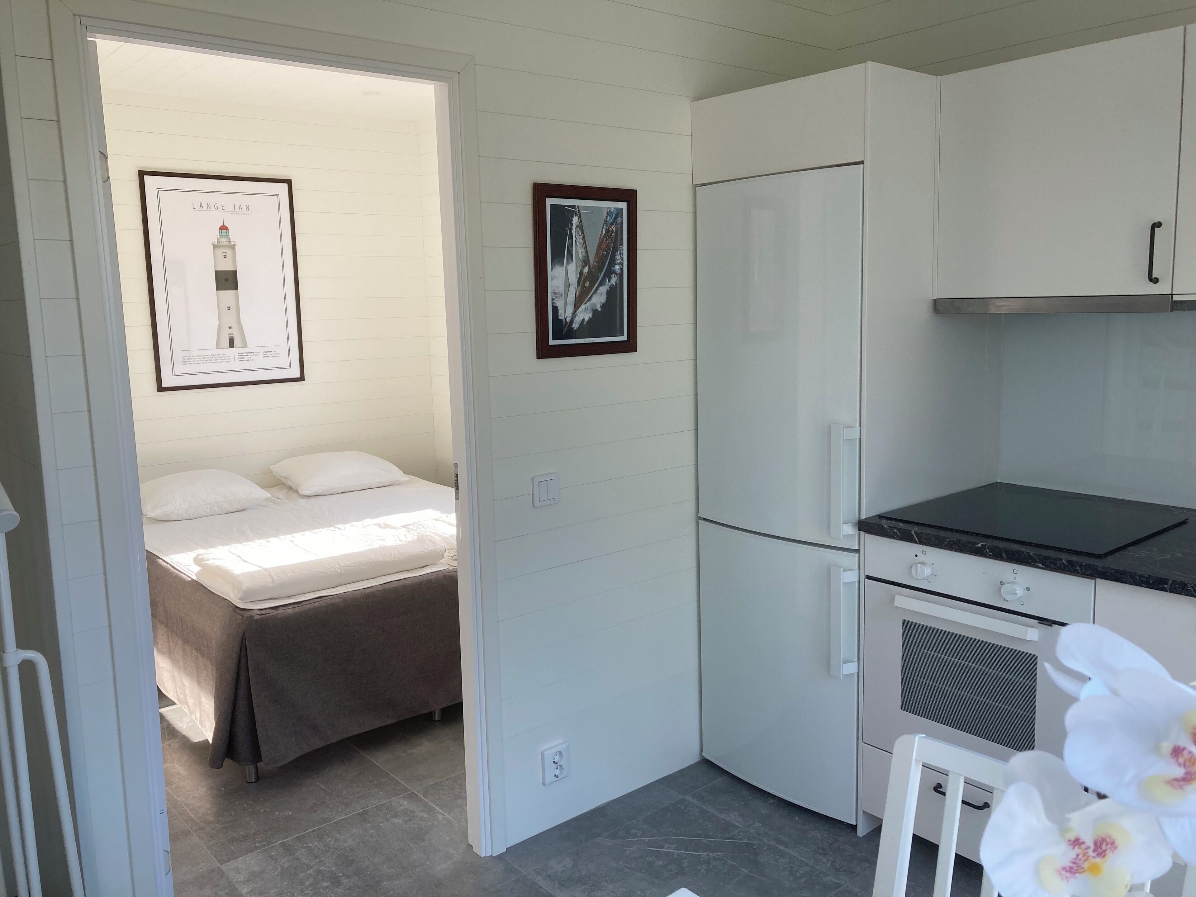 A compact kitchen with a refrigerator, oven, and a small dining table.