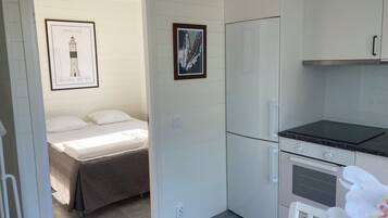 A compact kitchen with a refrigerator, oven, and a small dining table.