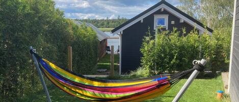 A hammock in a grassy backyard with a house in the background.