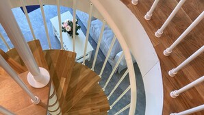 A spiral staircase with white railings and wooden steps. - Brygghuset (Rockneby)