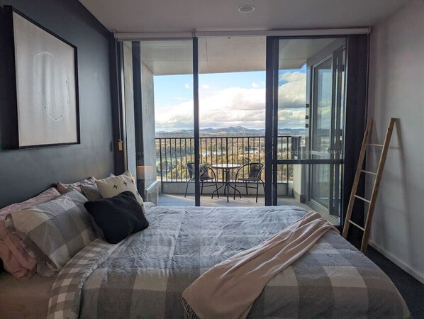A bedroom with a large bed, a balcony with a view, and a ladder.