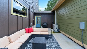 Une terrasse extérieure avec un canapé d’angle, une petite table et un espace barbecue.