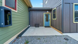 Un bâtiment à l’extérieur vert, avec une porte bleue et une borne de recharge pour véhicules Tesla.