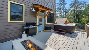 Una terraza con parrilla, bañera de hidromasaje y fogata.
