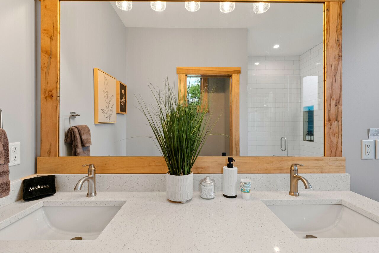 A bathroom with two sinks, a large mirror, and a potted plant.