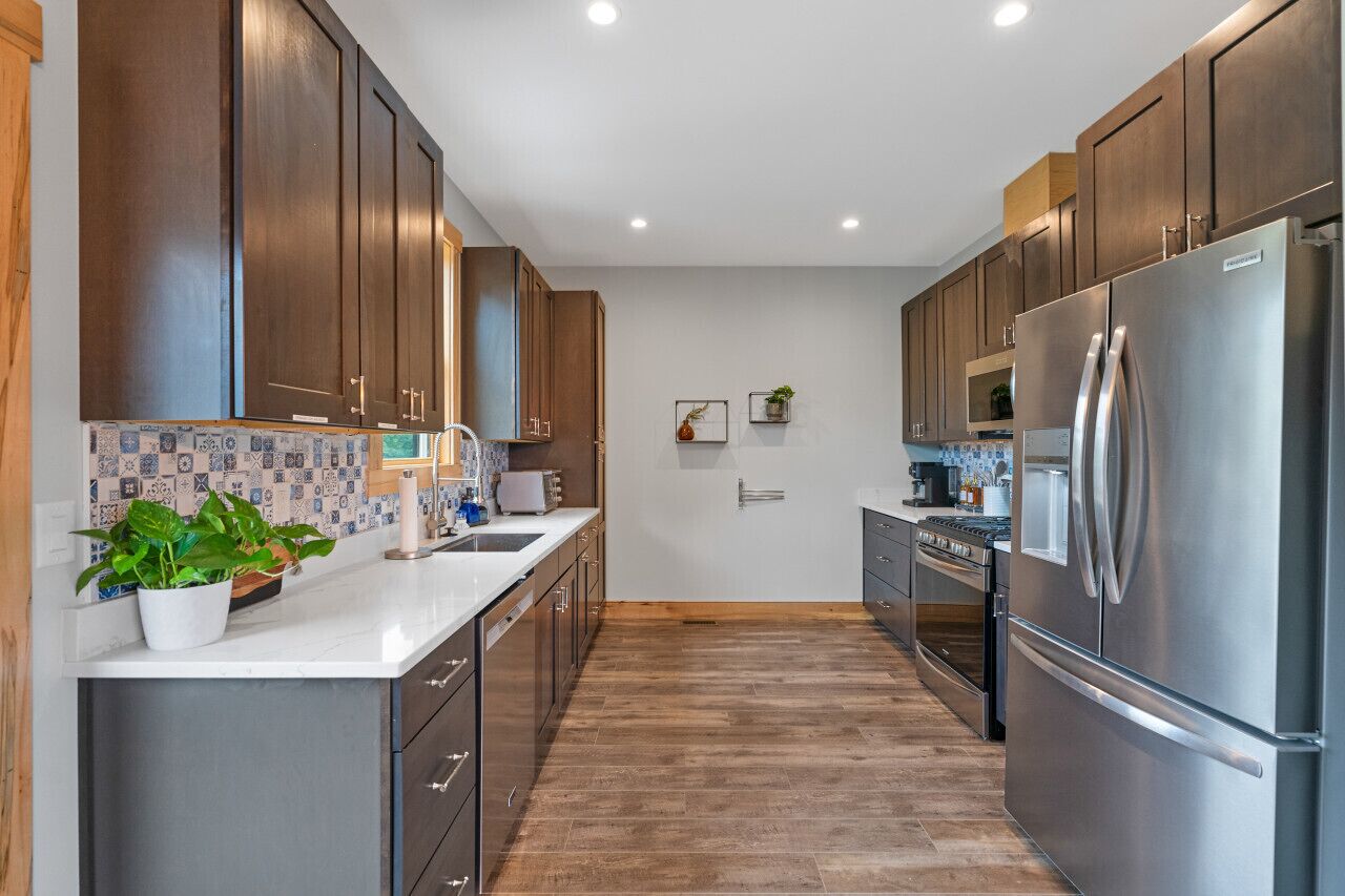 A modern kitchen with dark wooden cabinets, stainless steel appliances, and a tiled backsplash.
