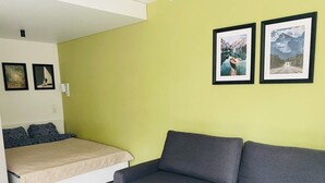 Een knus woongedeelte met een bed, een bank en twee ingelijste foto's aan de muur.
