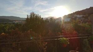 A balcony with potted plants, overlooking a hillside with buildings. - Casa Rural Cortijo Paulenca  (Almería)