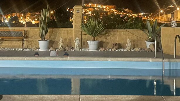A nighttime pool area with a clear view of a cityscape in the background. - Casa Rural Cortijo Paulenca  (Almería)