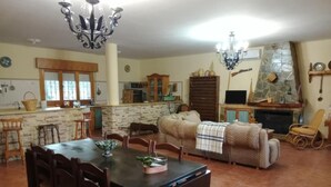 A spacious living room with a dining area, a fireplace, and a kitchen in the background. - Casa Rural Cortijo Paulenca  (Almería)