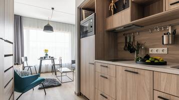 A modern kitchen with wooden cabinets, a built-in oven, and a fruit bowl on the counter.