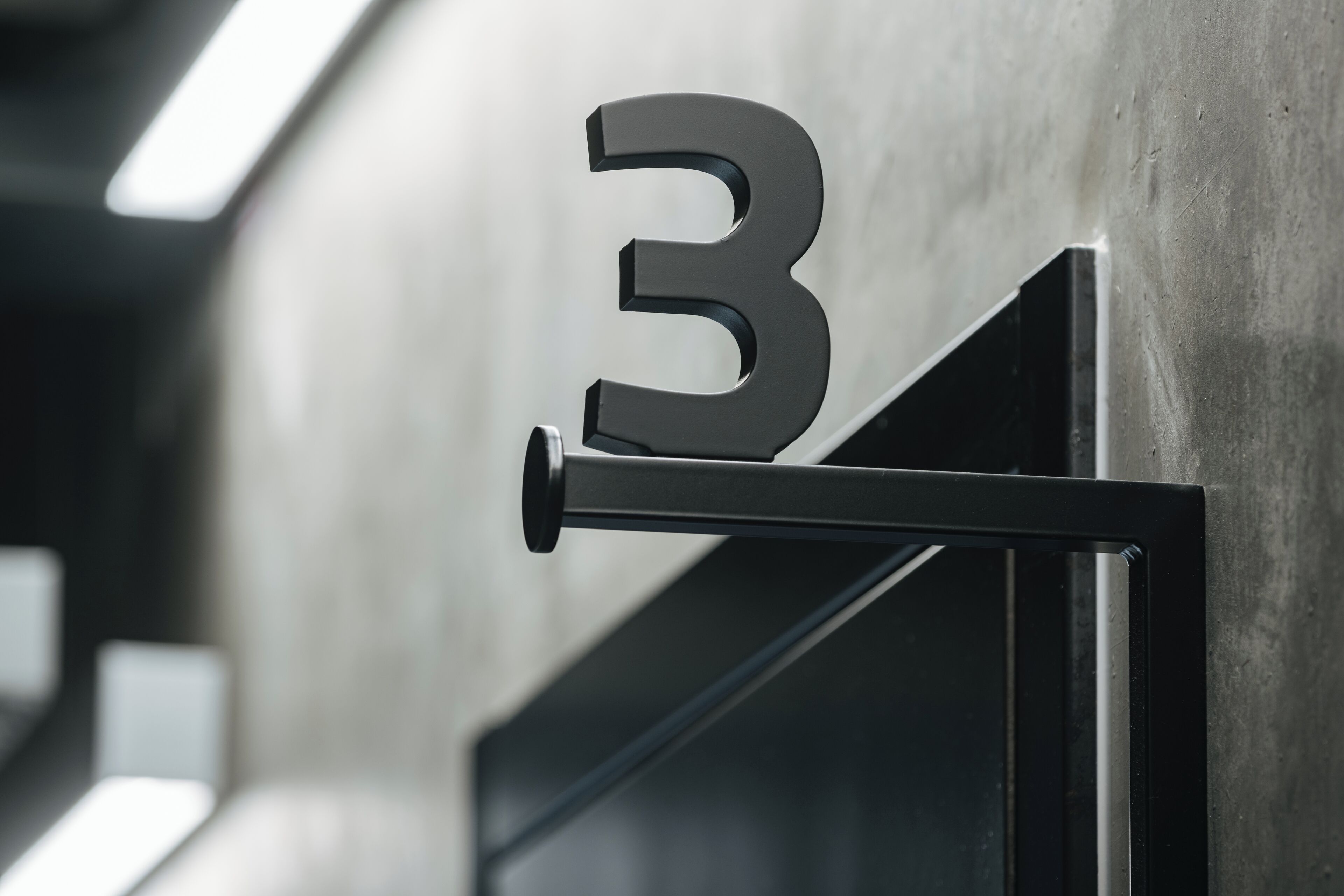 A close-up of a metallic number '3' sign on a wall, likely indicating a room or section number in a building.