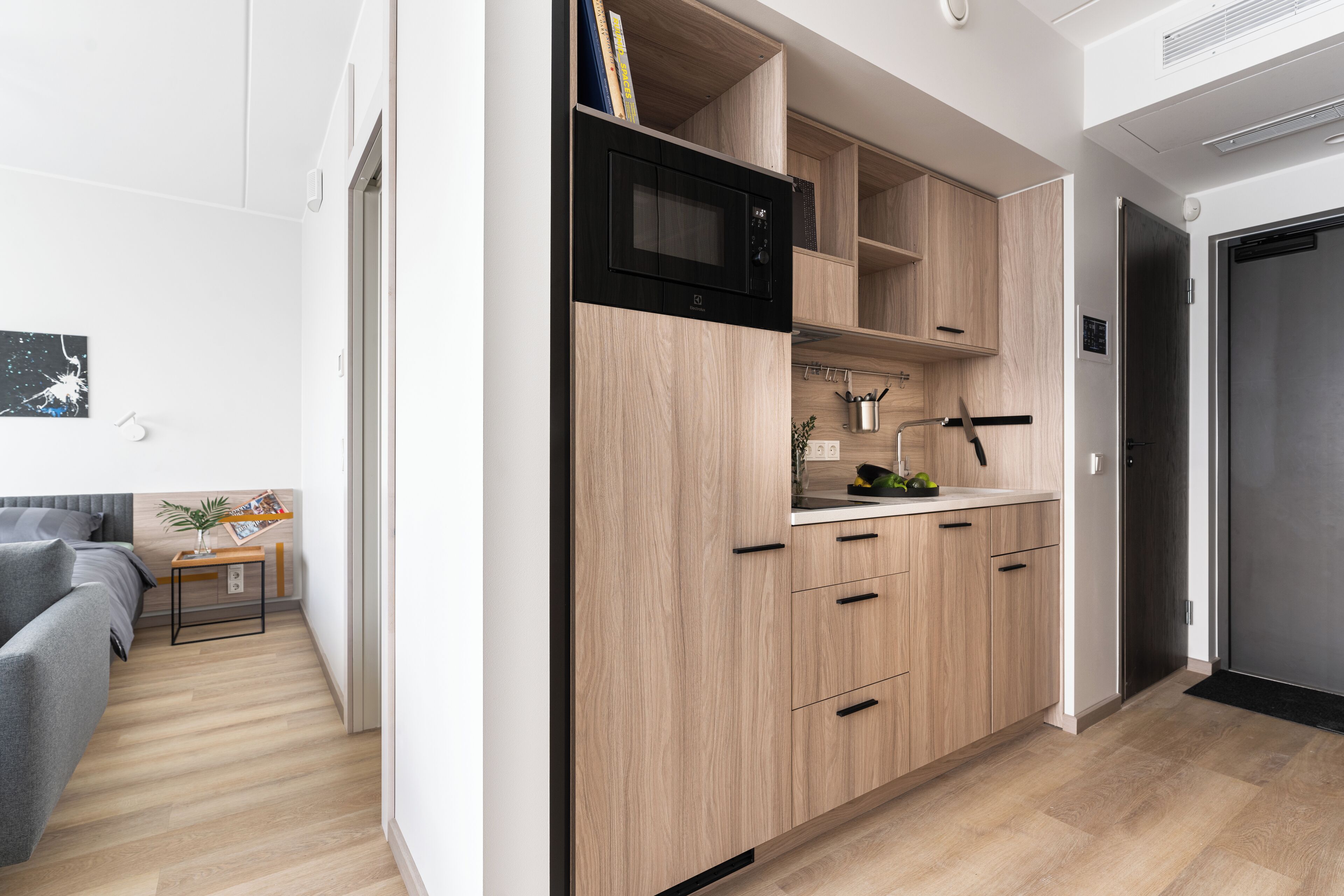 A modern kitchen with wooden cabinets, a black microwave, and a stainless steel refrigerator.